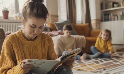 Mutter lernt Spanisch während die Kinder im Hintergrund spielen